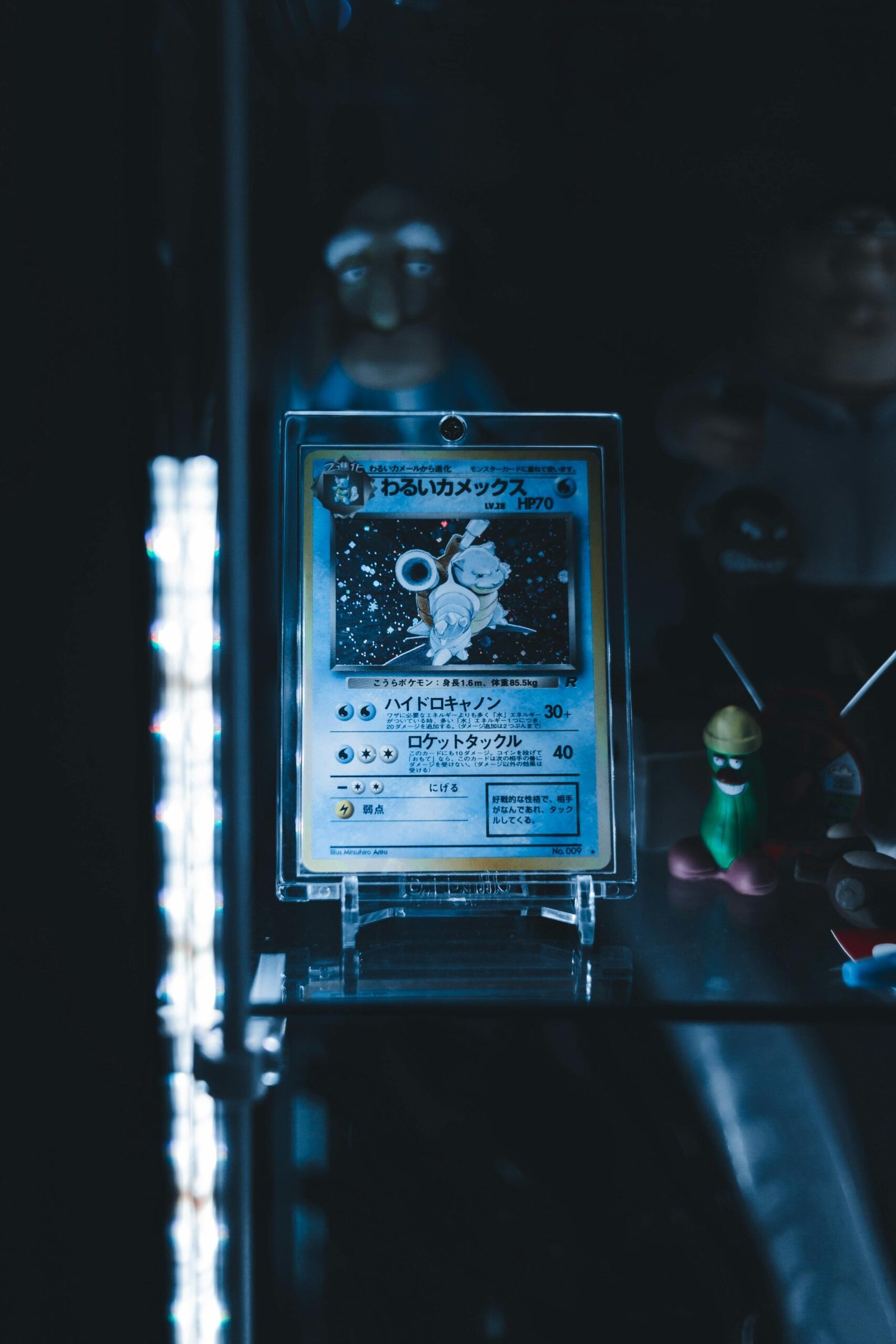 Rare Pokémon card displayed in a dimly lit shelf with character figurines.